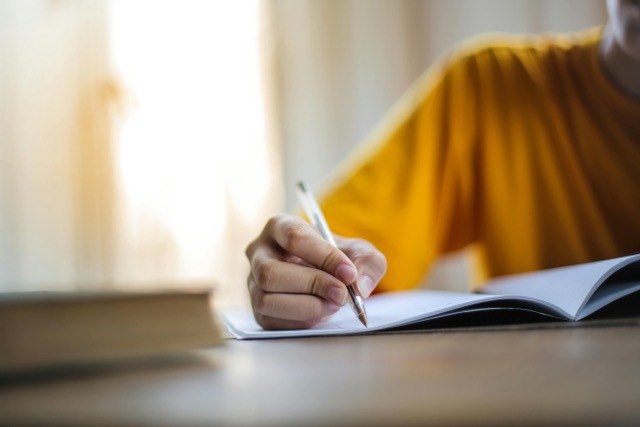 hand using pen to write on paper