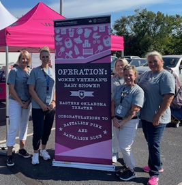 Eastern Oklahoma VA Women Veterans Program team pose with Operation Women Veterans Baby Shower banner