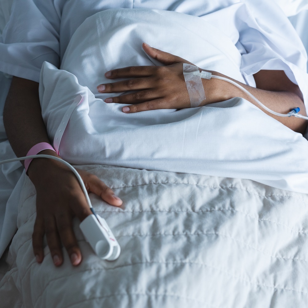 Person's hands with IV tubes lying in a bed