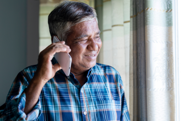 A person looks out the window while talking on the phone.