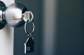 Home key with metal house keychain in keyhole.