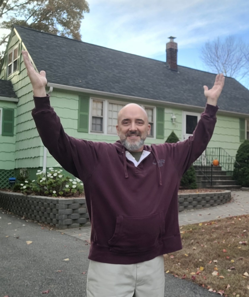 Michael Magyar raising hands in front of his home