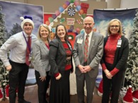 a group of people smiling and wearing holiday themed outfits