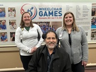 two people standing behind a person in a wheelchair 