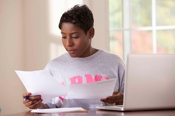 A person sits at a desk and looks through papers.
