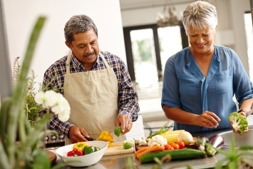 Two people prepare vegetables in the kitchen.