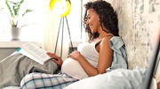 Smiling pregnant woman sitting in bed.