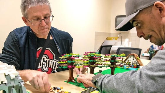 Two men are working to put a Lego community together.
