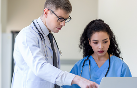 Clinicians looking of computer monitor, discussing medical document and consulting.