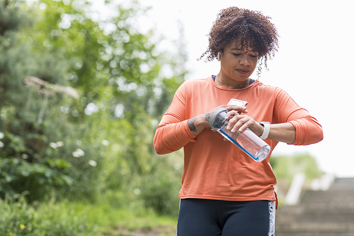 A woman dressed to exercise checks her watch.
