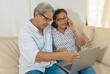 Two people sitting down looking at a computer.