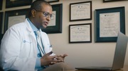 A doctor is speaking to a patient on his laptop.