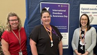three people standing in front of overdose awareness sign 