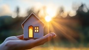 Hands holding a house over sunset