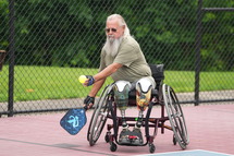 person in wheelchair hitting a ball with paddle 
