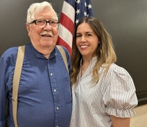 two people in front of flag smiling 