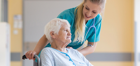 Senior woman in wheelchair with nurse in hospital.