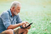 Older man sitting and using this phone