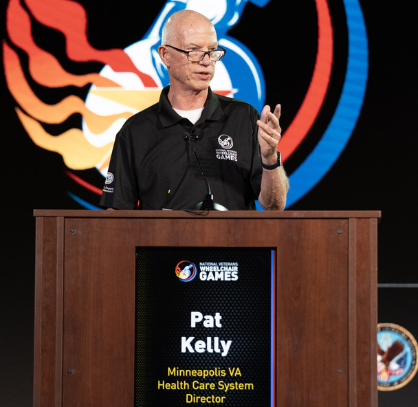 person on stage behind podium at wheelchair games