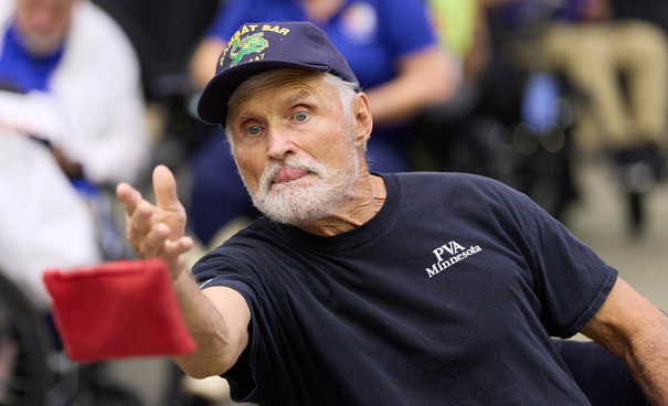 person in wheelchair throwing a bean bag