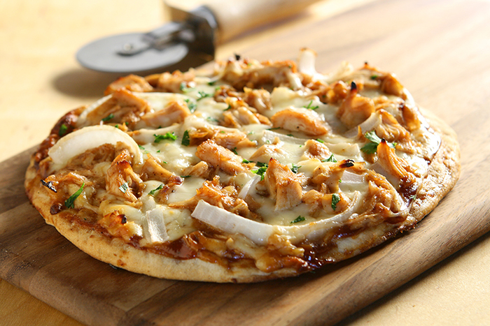 A barbeque chicken pizza waits to be eaten.