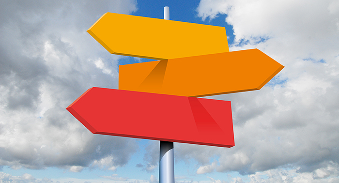 Bright directional signs against a blue sky and puffy clouds.