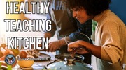Two people cooking together in a kitchen filled with fresh vegetables and cookware.