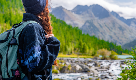 Woman looking towards mountains and river.