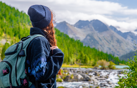 Woman looking towards mountains and river.