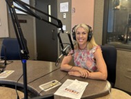 person in radio studio with headphones and microphone smiling 