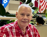 a person sitting in front of a line of flags smiling 