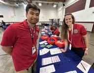 a man and women wearing matching polo shirts at a table with brochures