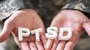 Close-up of hands holding white letters spelling PTSD.