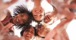 A group of women Veterans in a circle, looking down at the camera in the center of the circle