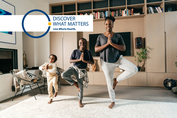 A woman and her young children strike yoga poses together.