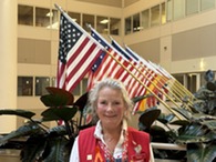 person wearing a red vest standing in front of flags