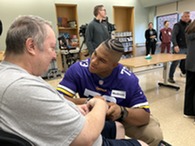 a football player wearing a jersey and holding the hand of a person in a wheelchair 