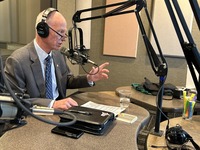 a man in a suite and tie in a recording studio with a microphone and headphones