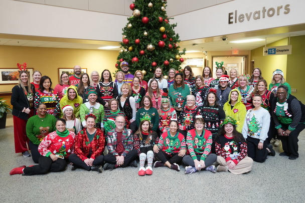 a group of people in front of a tree wearing ugly sweaters 