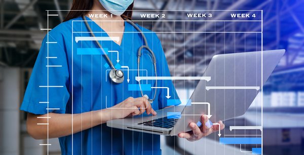 Nurse holding a laptop with a digital calendar.