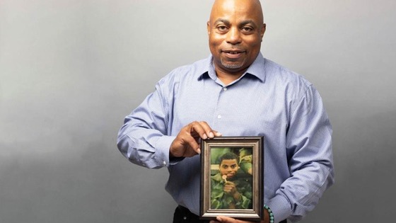 Charles Bazier holding a framed photo of  his younger self.