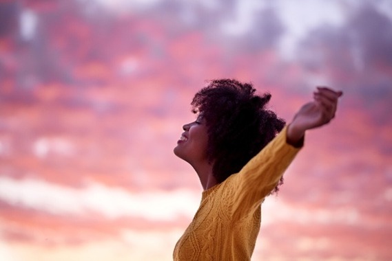 Woman stretching with purple and orange clouds behind her