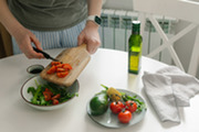 Woman preparing vegetable salad with tomato in the kitchen.