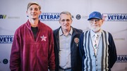 Three men standing in front of a National Disabled Veterans Winter Sports Clinic backdrop