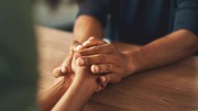 Two people holding hands across a wooden table