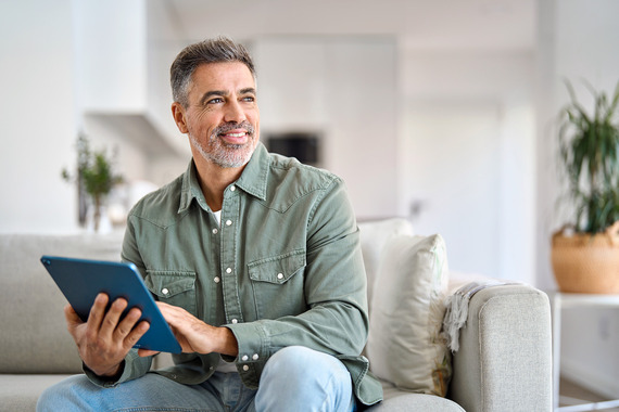 A smiling Veteran using a tablet to conduct a virtual tele pain session.