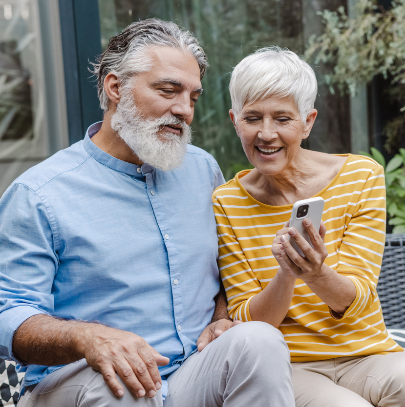 An older male and female looking at a smart phone together