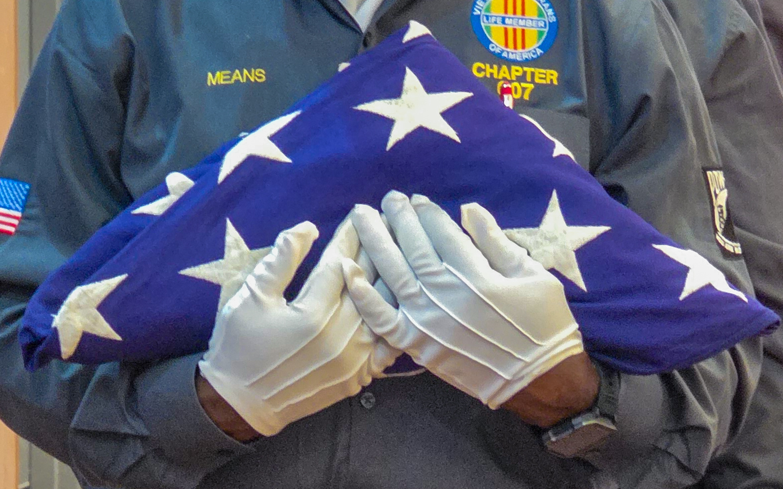 A Vietnam Veterans of America representative carries a folded American flag during the Interfaith Memorial Day Last Roll Call of Remembrance.