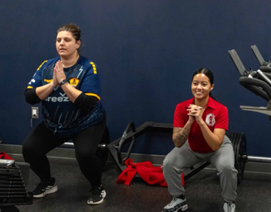 A Rhode Island FC trainer leads a Veteran through squats as part of a workout supporting the Go Red for Women heart health initiative. 