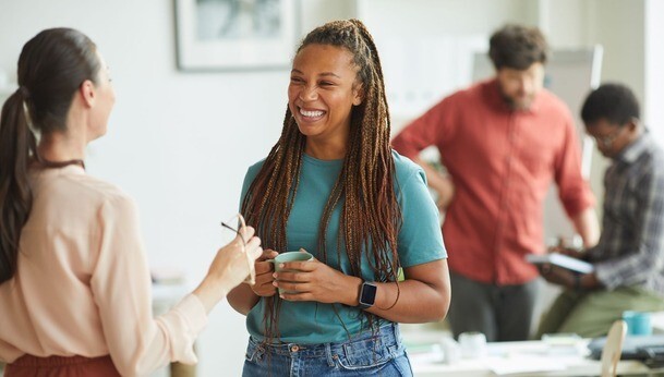 Two professional women smile and while having a conversation.